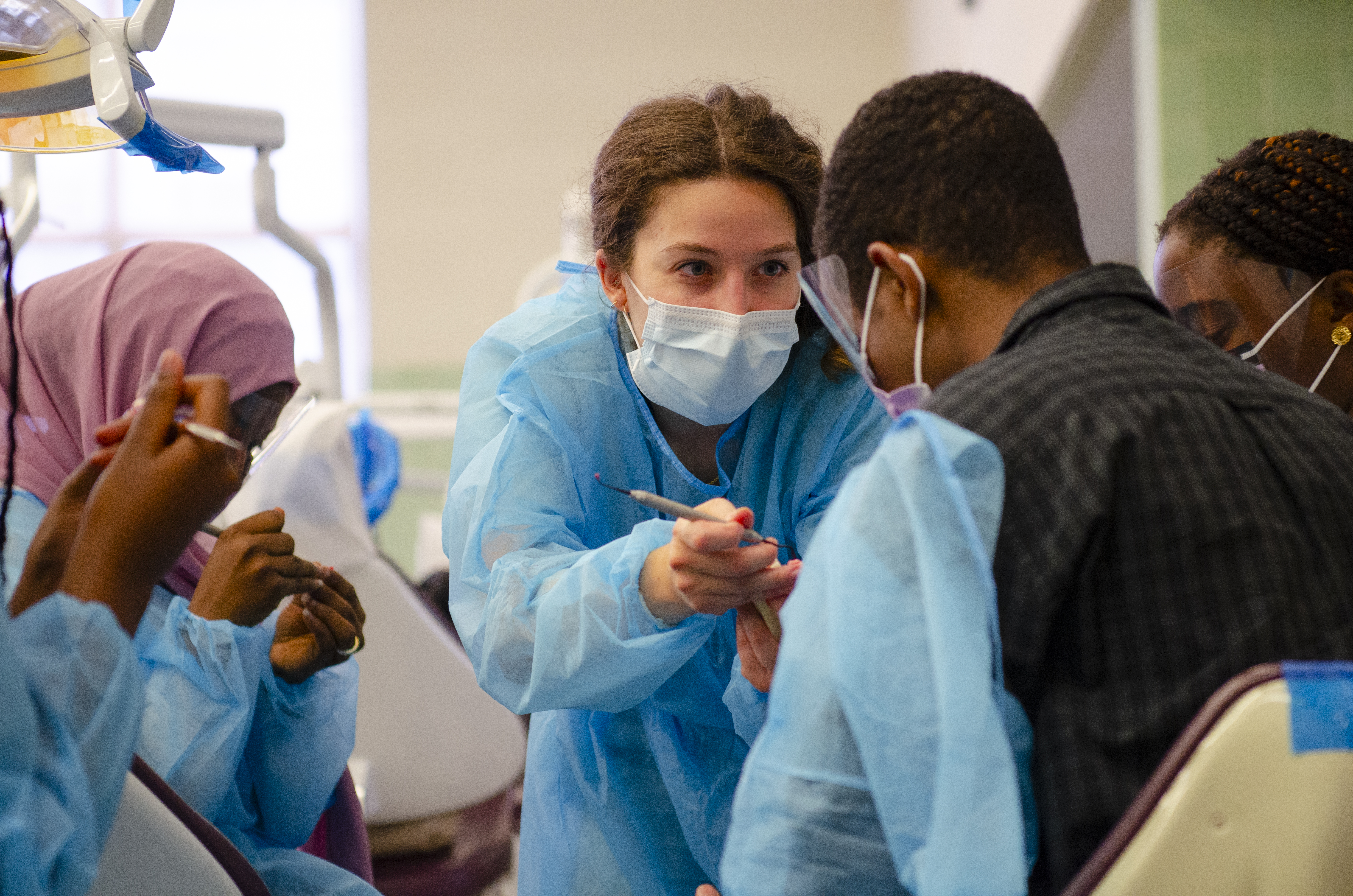 Two women dressed as dentists practising on a dummy head