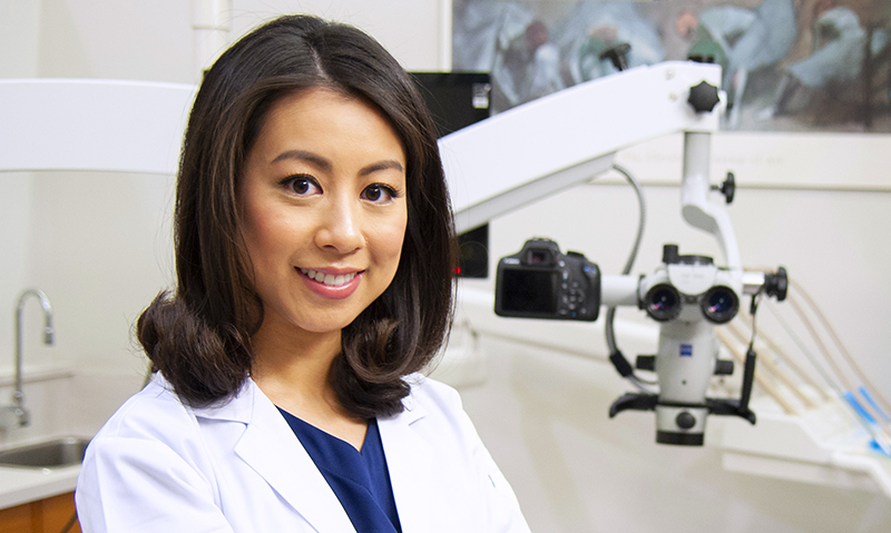 A female in a white coat sitting beside dental equipment