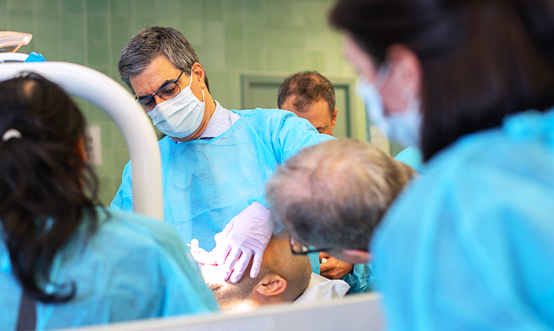 A dentist working on a patient whilst others watch