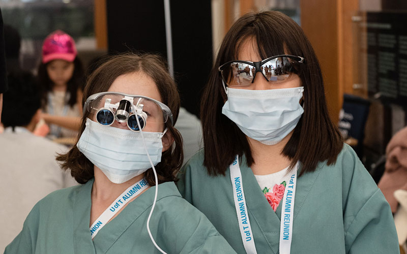 Two women with masks and scrubs on at an event for children