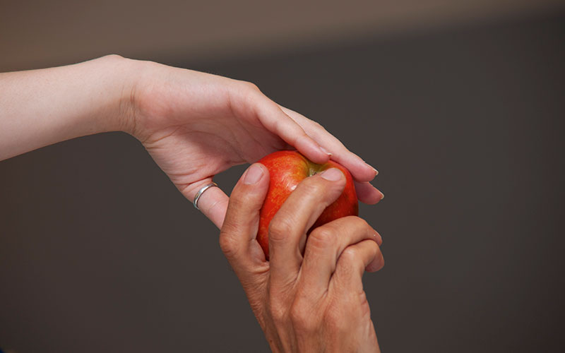 Two hands passing an apple