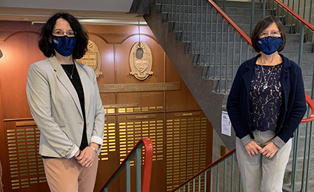 Celine Leveque and Siew-Ging Gong in the Faculty hallway wearing face masks