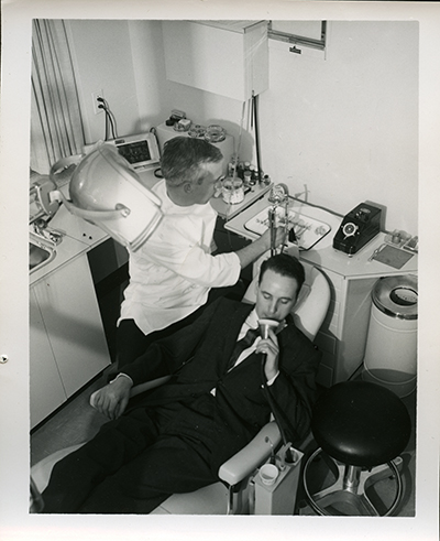 camera shot of dentist working on patient who is using spitoon