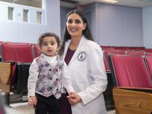 student in white coat with child