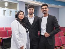 student in white coat with two people