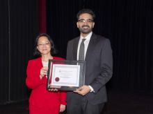 two people smiling and holding award