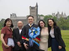 grad student and family smiling in front of building