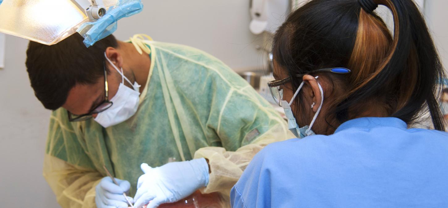 elderly patient receives treatment from dentist and hygienist