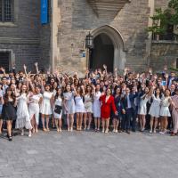 group of graduating students raising their hands up