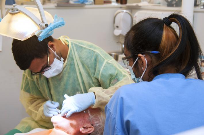 elderly patient receives treatment from dentist and hygienist