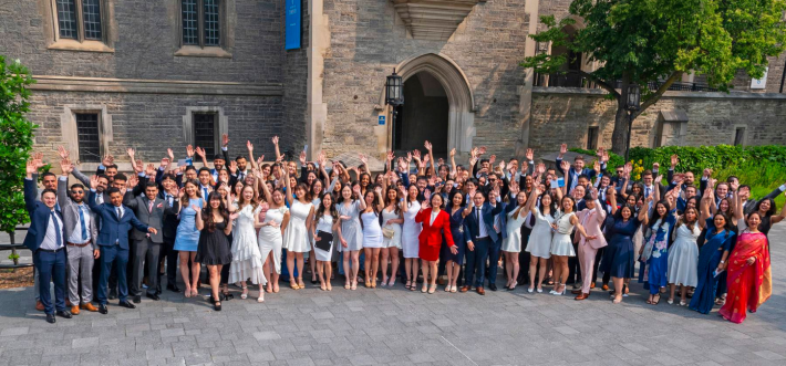 group of graduate students holding hands up in the air