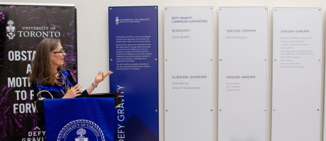 Photo of Elizabeth MacSween speaking next to the donor wall. 