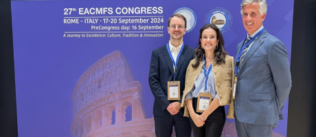 Dr. Caminiti (right), Dr. Cuddy (left), and  Dr. Franco (centre) in front of a banner