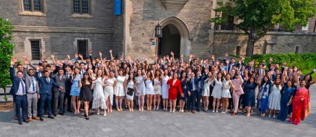 group of graduate students holding hands up in the air